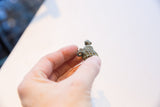 Vintage African turtle pendant held to scale, showing its textured, oxidized finish.