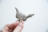 Vintage bronze snake pendant held to display its rustic texture and form.