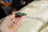 Side profile of a vintage bronze crocodile pendant with detailed texture and patina.