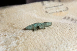 Vintage African bronze crocodile pendant in profile, showing textured scales and a green patina.