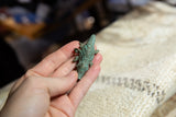 A vintage bronze crocodile pendant held in hand to show its scale and textured green patina.