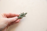 The hollow underside and textured detail of a vintage bronze crocodile pendant.