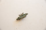 Angled view of the vintage crocodile pendant highlighting the textured bronze and green patina.
