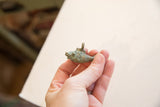 Side profile of the vintage African fish pendant showing its etched spirals and bronze patina.