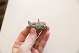 Vintage African bronze fish pendant with textured scales and an aged green patina.