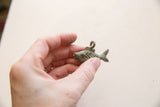 Vintage African bronze fish pendant held in hand to demonstrate scale.