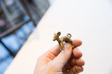 Side profile of the vintage African impala pendant held to display its small size.