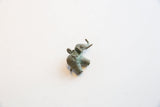 Angled view of a vintage bronze elephant pendant showing its textured surface and weathered patina.
