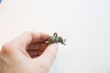 Side view of the small bronze elephant pendant showing its oxidized finish and spiral details.