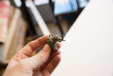 A hand holding the small vintage bronze elephant pendant to show its scale and oxidized finish.