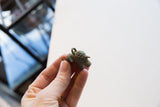 Vintage bronze elephant pendant held in hand, showing its textured details and small scale.