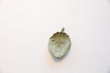 The concave reverse side of the vintage bronze face pendant with its textured, aged patina.
