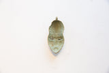 Reverse side of a vintage bronze pendant showing its concave interior and aged patina.