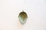 Aged green and brown patina inside the concave vintage bronze face pendant.