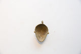 The concave back and aged patina of the vintage bronze face pendant.