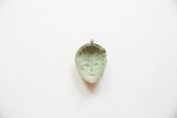 Aged green patina on the concave interior of a vintage African bronze face pendant.