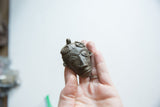 Vintage African bronze face pendant held to show its scale and texture.