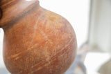 Time-worn patina and earthy texture of the antique red slip ware vase.