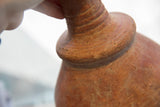 Earthy red slip ware texture and hand-thrown ridges on the antique vase's neck.