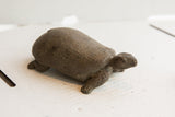 Side view of the hand-carved tortoise sculpture revealing its aged, textured finish.