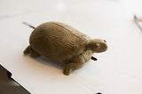 Side profile of the vintage tortoise sculpture showing its carved shell and textured body.