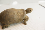 Side view of a vintage tortoise sculpture with hand-carved geometric shell patterns.