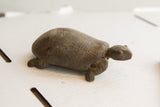 Side view of handmade tortoise sculpture with rustic texture and etched shell design.
