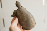Earthen-toned African tortoise sculpture held to show the carved details of its shell.