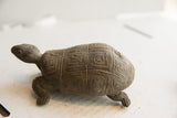 The dark, earthy form of the vintage African tortoise sculpture seen in profile.