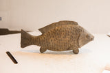 Side profile of a vintage African fish sculpture showing its rustic, hand-carved scales.