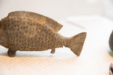 Angled view of the vintage fish sculpture highlighting its carved tail and textured scales.