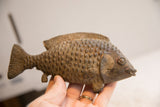 Side view of the vintage fish sculpture held to show its handmade texture.