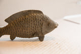 Profile view of a vintage African fish sculpture with textured scales and carved fins.