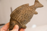 Handmade African fish sculpture held to show its tactile, textured scales and size.