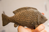Vintage African fish sculpture held in hand to demonstrate its scale and rustic texture.