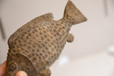 The tactile, raised scales and carved tail fin of a vintage African fish sculpture.