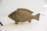 Side profile of a hand-carved fish sculpture with textured scales and fins.