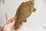 Handmade African fish sculpture held in hand, showing its textured scales and size.