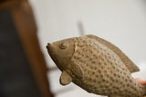 Angled close-up of the vintage African fish sculpture's head and textured scales.