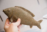 The collectible African fish sculpture held, showing its handcrafted texture and size.