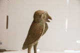 Vintage African owl sculpture in profile, showing its open beak and rough, aged patina.