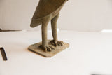 The owl sculpture's textured talons gripping its flat, square base.