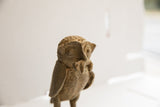 Close-up of the vintage owl sculpture's face, highlighting its textured surface and prey.
