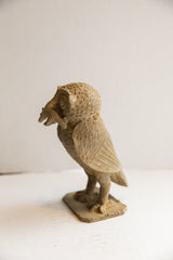 Textured African owl sculpture in profile, with a rat held firmly in its beak.
