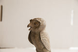 Profile view of the vintage owl sculpture's head, showing its open beak and handmade texture.