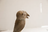 Profile view of the vintage owl sculpture's textured head and open beak.