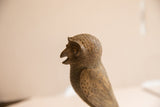 Profile of a vintage African owl sculpture showing hand-carved texture and open beak.