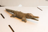 Profile view of a handmade African crocodile showing its detailed carved texture.