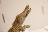 Upward view of the vintage crocodile sculpture's head, highlighting its carved details.