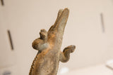 Textured details of the vintage crocodile sculpture's head and forelegs from a low angle.